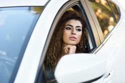 Female with curly hair resting chin on hand out driver’s window