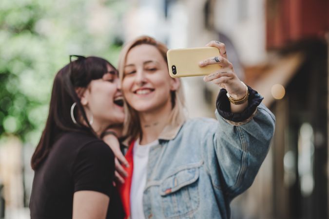 Happy lesbian couple taking selfie on street