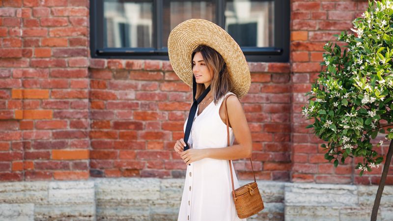 Woman walking next to brick building in summer time