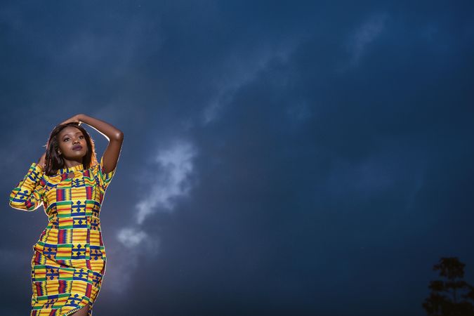Woman in blue yellow dress standing under night sky