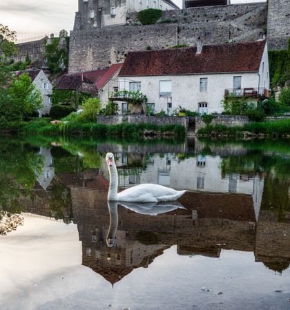 The medieval walled city of Pesmes in Burgundy. Reflection in the river at sunset.