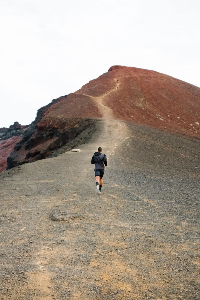 Back of man jogging up rugged hill
