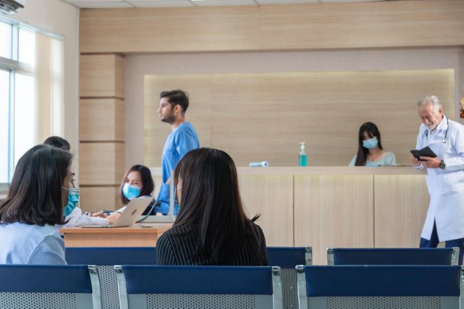 Patients in hospital waiting room with doctor reading notes