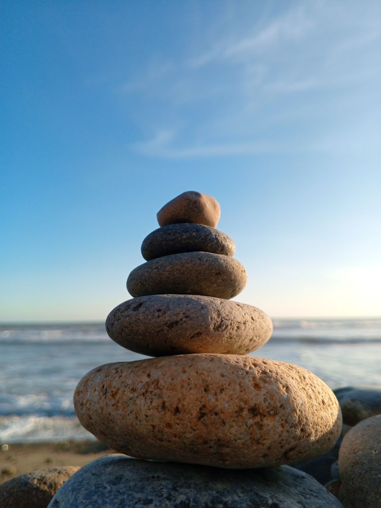 Arrangement of rocks on the beach with calm waves in the background.