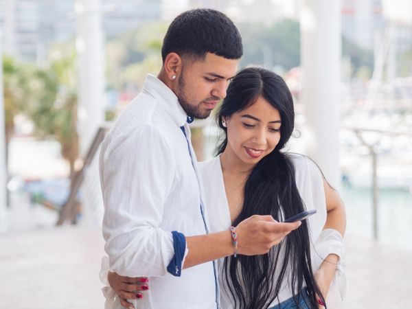 Man messaging on smartphone standing with woman