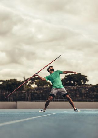 Man in position to throw a javelin in a track and field stadium
