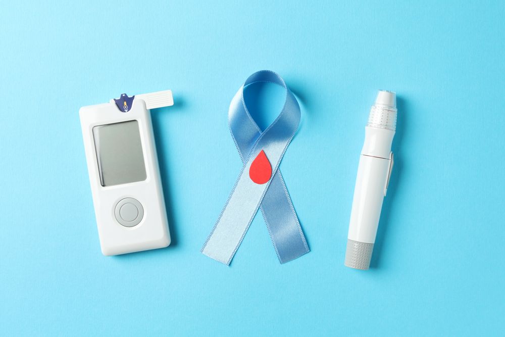 Blue awareness ribbon and diabetes accessories on blue background