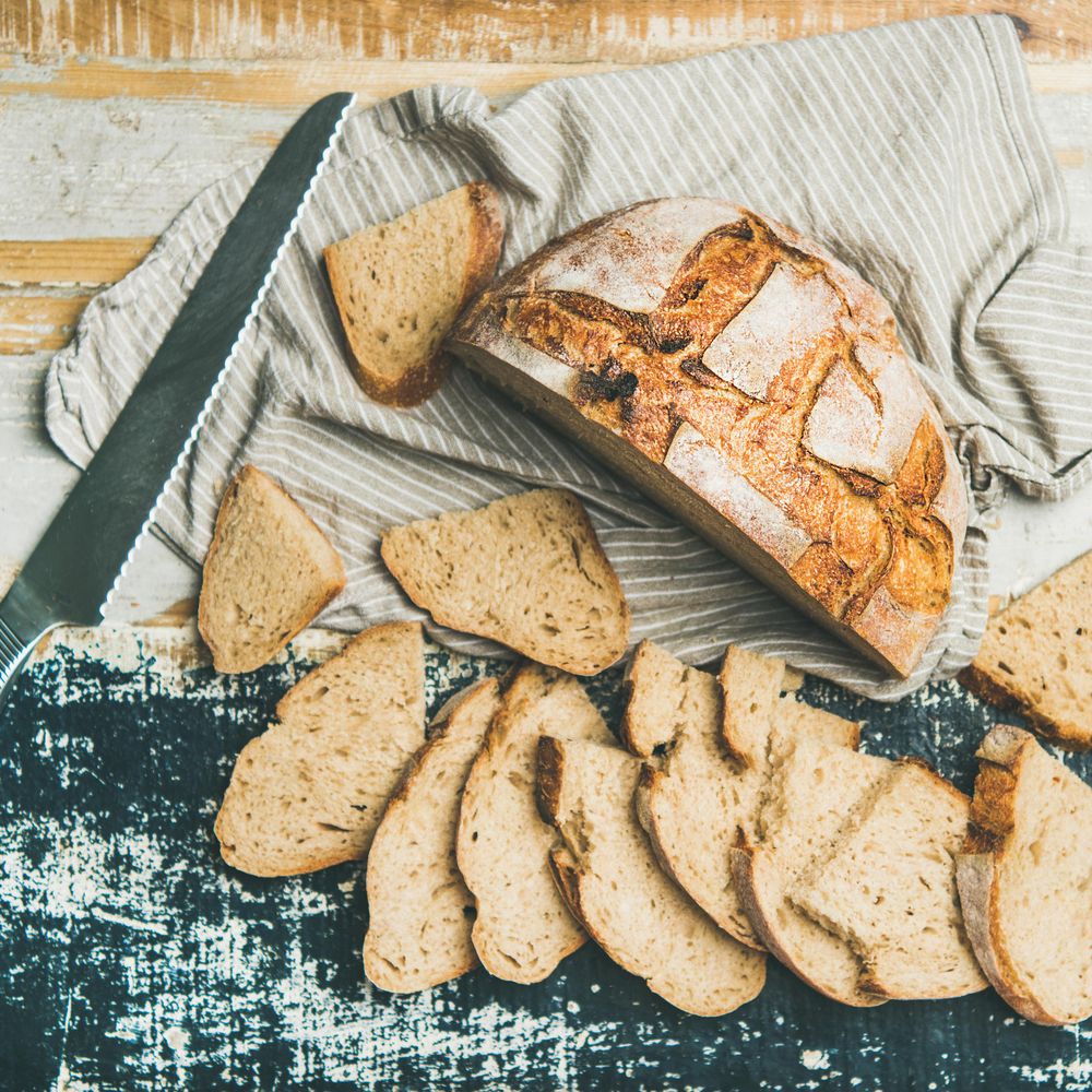 Homemade loaf of sliced bread on wooden board and linen cloth