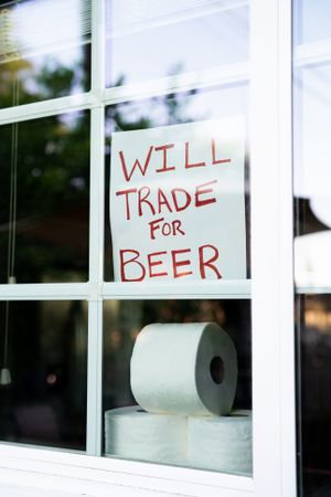Window sign asking to trade toilet paper for beer