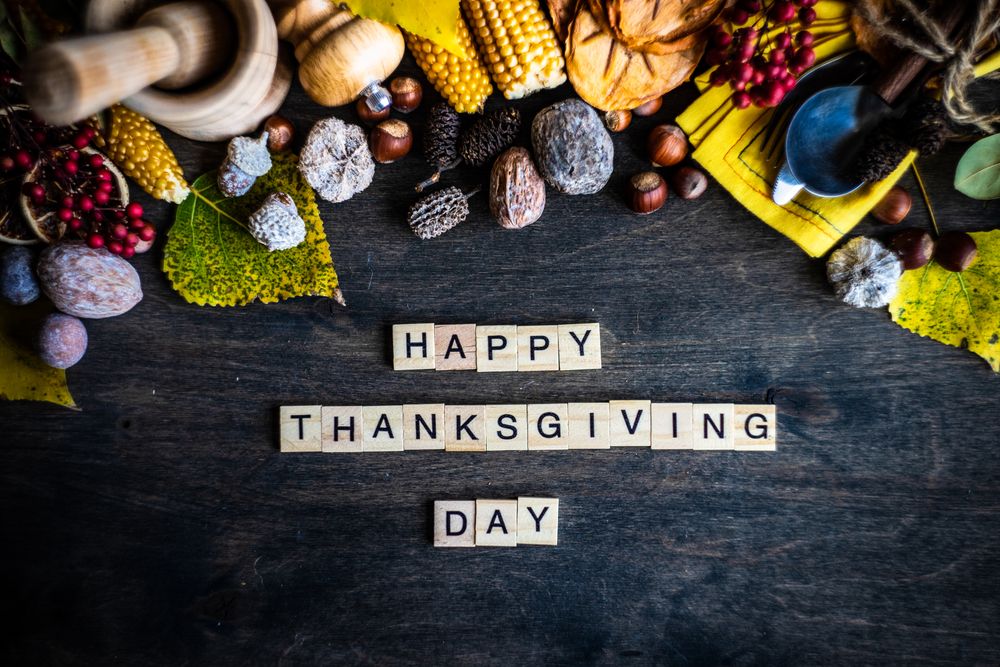 Top view of Happy Thanksgiving message on table with nuts, berries, vegetable and fruits