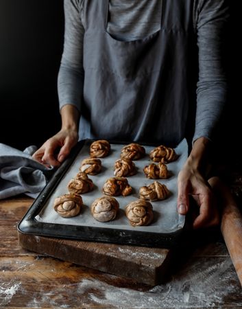 Crop woman with baking pan of cardamom buns