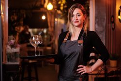 Cheerful waitress holding tray with wineglasses