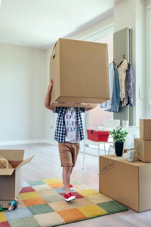 Boy carrying very large moving box