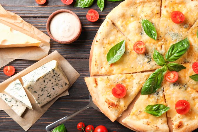 Cheese pizza and ingredients on wooden background, top view