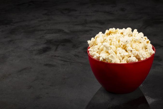 Bowl with salted popcorn sore the table.