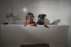 Boy in diving mask near dog in tub