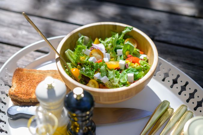 Bowl of healthy salad with toast served on tray