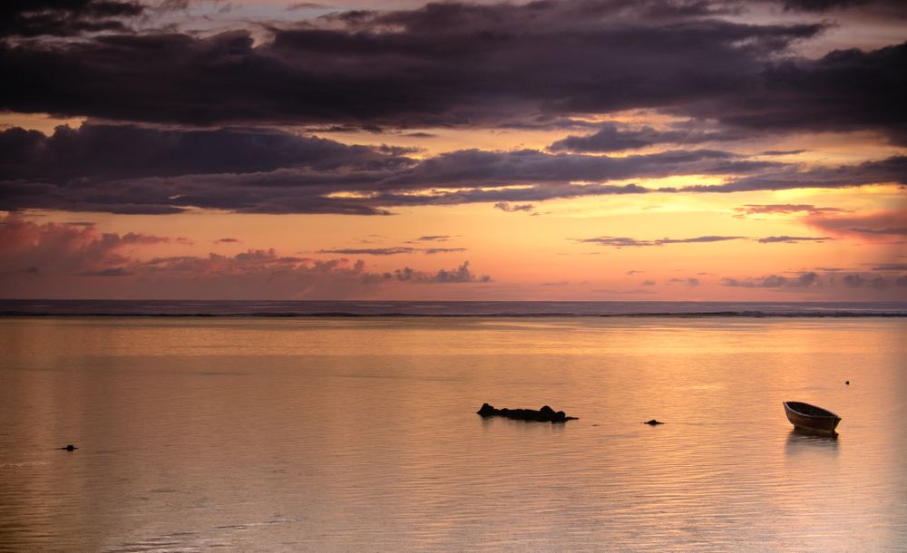Boat and rocks under clouds forming at dawn