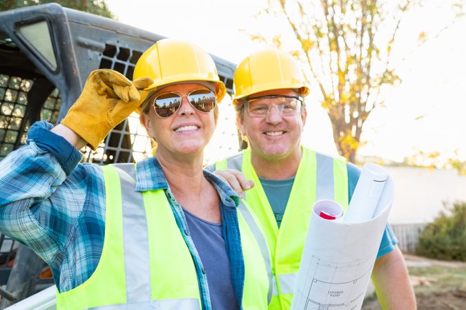 Male and Female Workers With Technical Blueprints at Construction Site