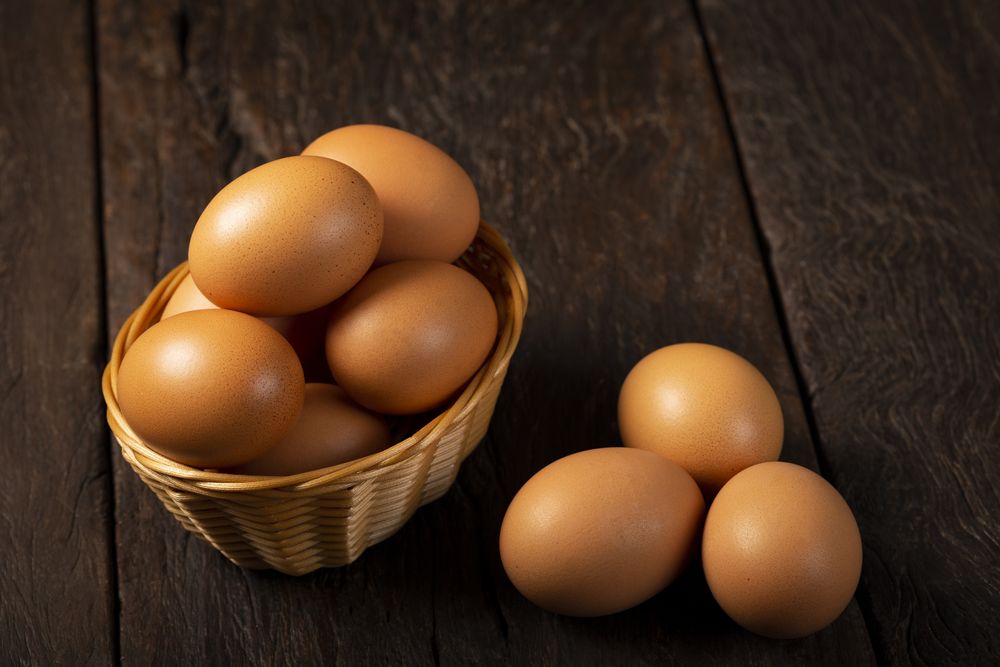 Basket with brown chicken eggs goes up the table.