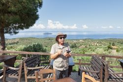 older man with smartphone on terrace with seascape