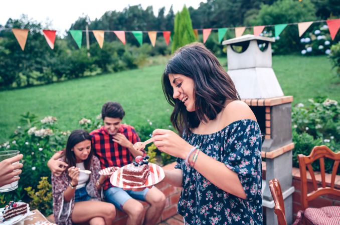 Woman eating piece of cake at summer party