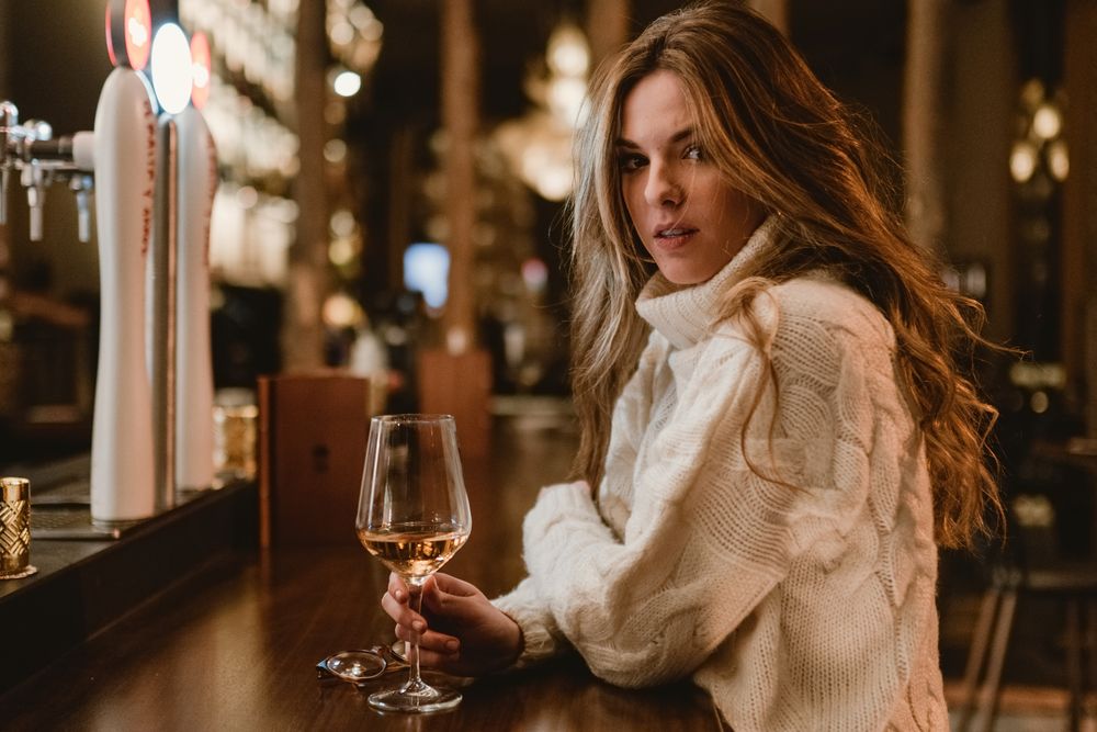 Stylish woman drinking wine in bar