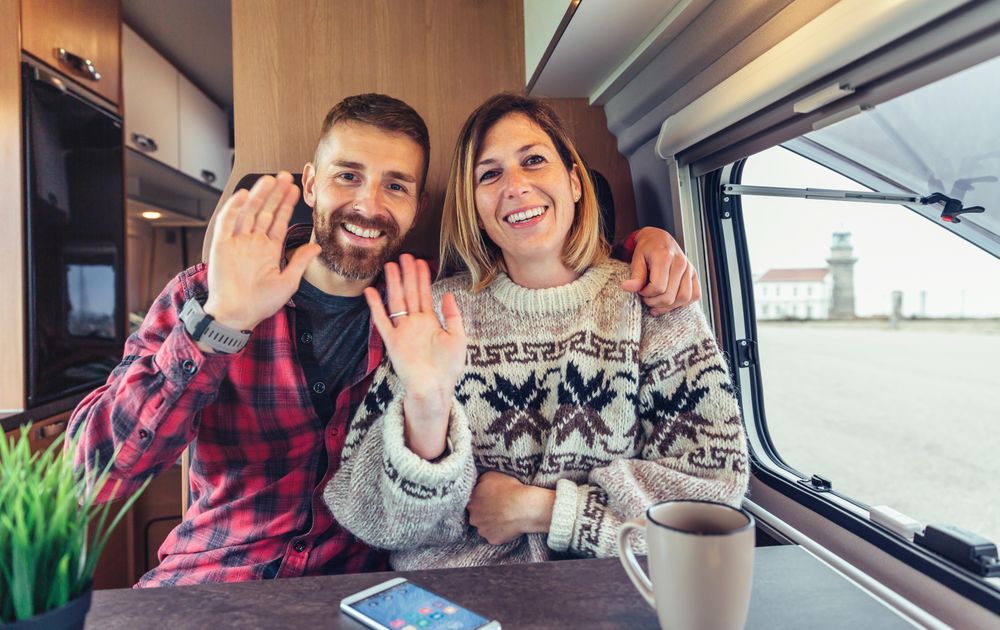 Friendly man and woman waving at camera as if chatting on video call