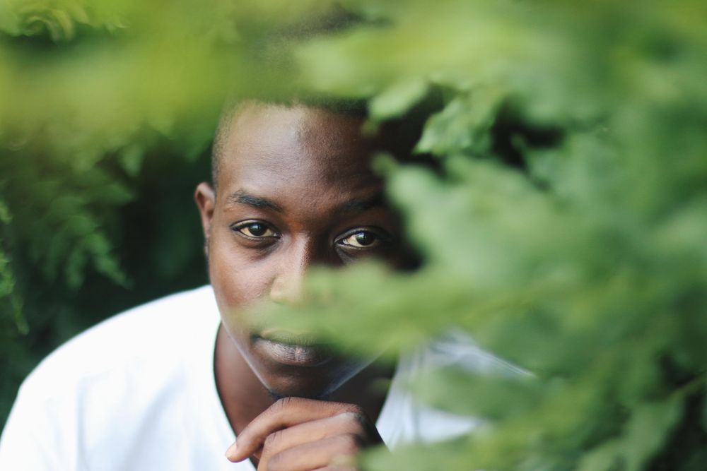 Man in light shirt posing between green leaves