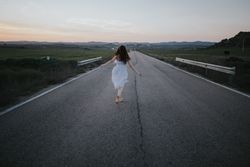 Anonymous woman running along countryside road