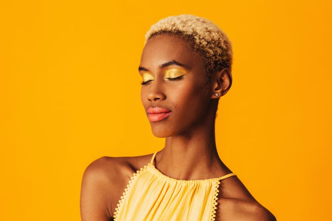 Black woman with short blonde hair with her eyes closed