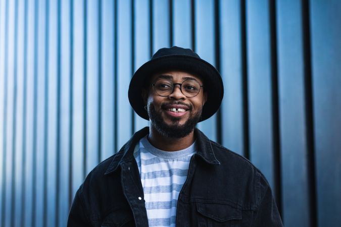 Smiling Black hipster man in hat looking away