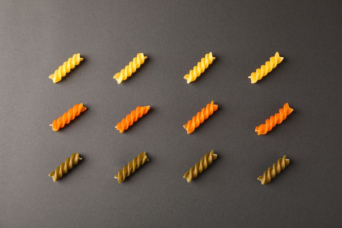 Flat lay composition with multicolored pasta on dark background, space for text