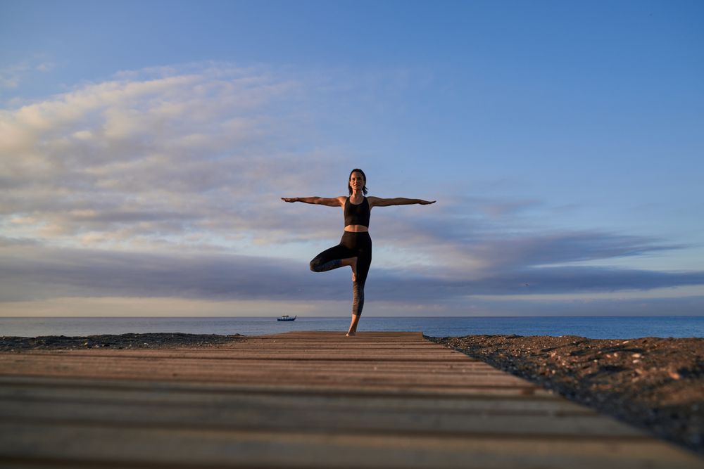 Fit woman practicing yoga on seashore