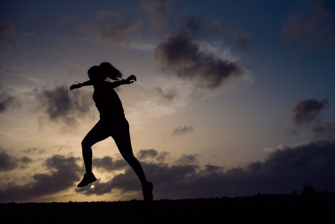 Jumping woman and sky with clouds at sunset