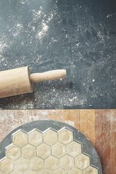 Top view of ravioli in mold on breadboard with rolling pin and scattered flour