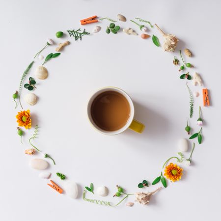 Circle around a cup of tea with summery items like flowers and seashells