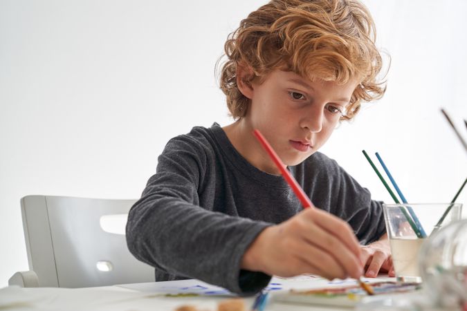 Cute boy painting with aquarelle