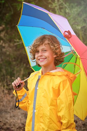 Cheerful boy with umbrella looking at camera and smiling