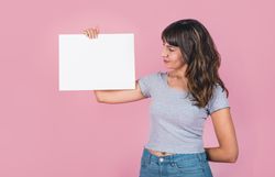 Woman holding a blank sign against a pink background