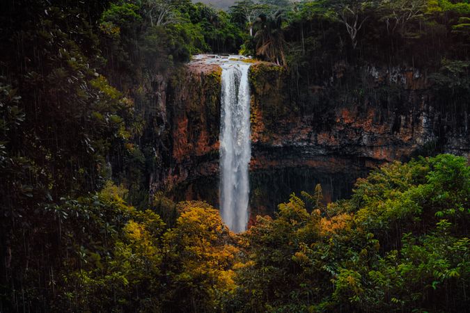 Water fall going over rocks into green and yellow vegetation