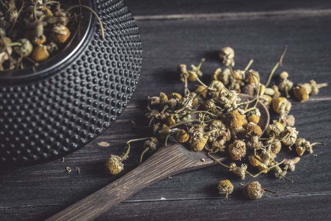 Spoonful of dried chamomile on wooden table