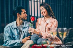 Asian man giving rose to his girlfriend on date night 5oDDeg