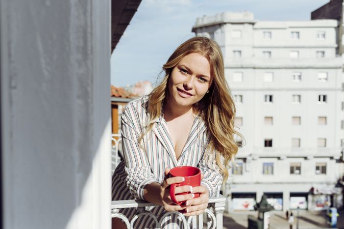 Young cheerful female with cup on terrace