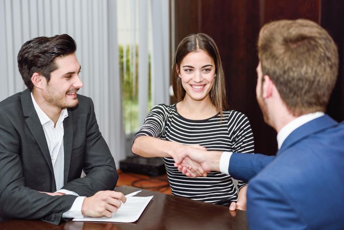 Man and woman shaking hands over a table in an office