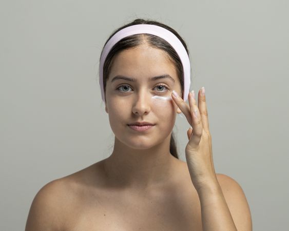 Eye cream skin care beauty routine: young woman in product application for under-eye treatment.