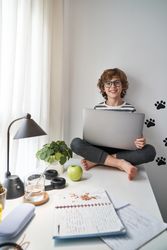 Smiling boy using netbook during online studies at home
