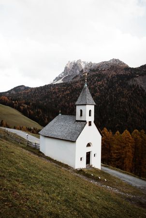 Small church on cliff near forest and mountains
