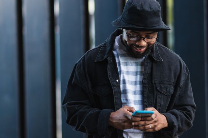 Positive Black hipster man using mobile phone