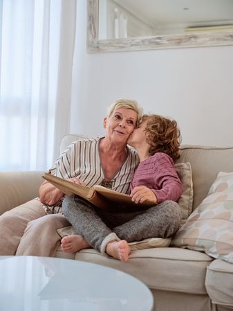 Grandson with curly red hair kissing granny by cheek